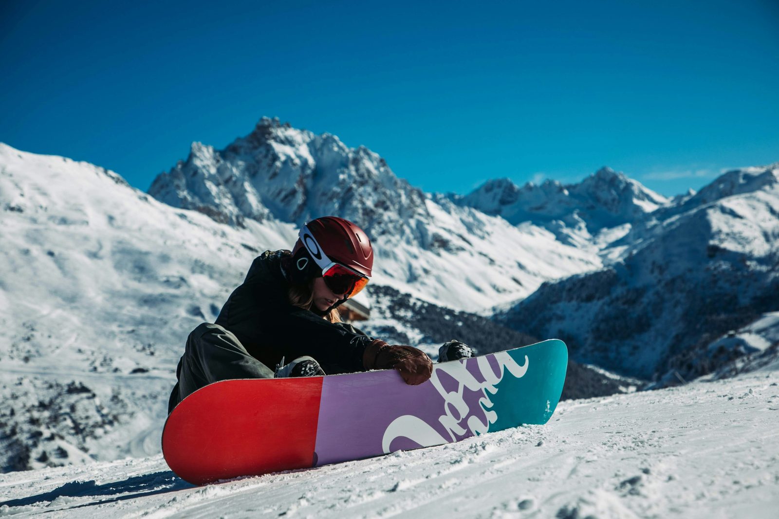 Snowboarder sitting on a slope with a mountain behind them