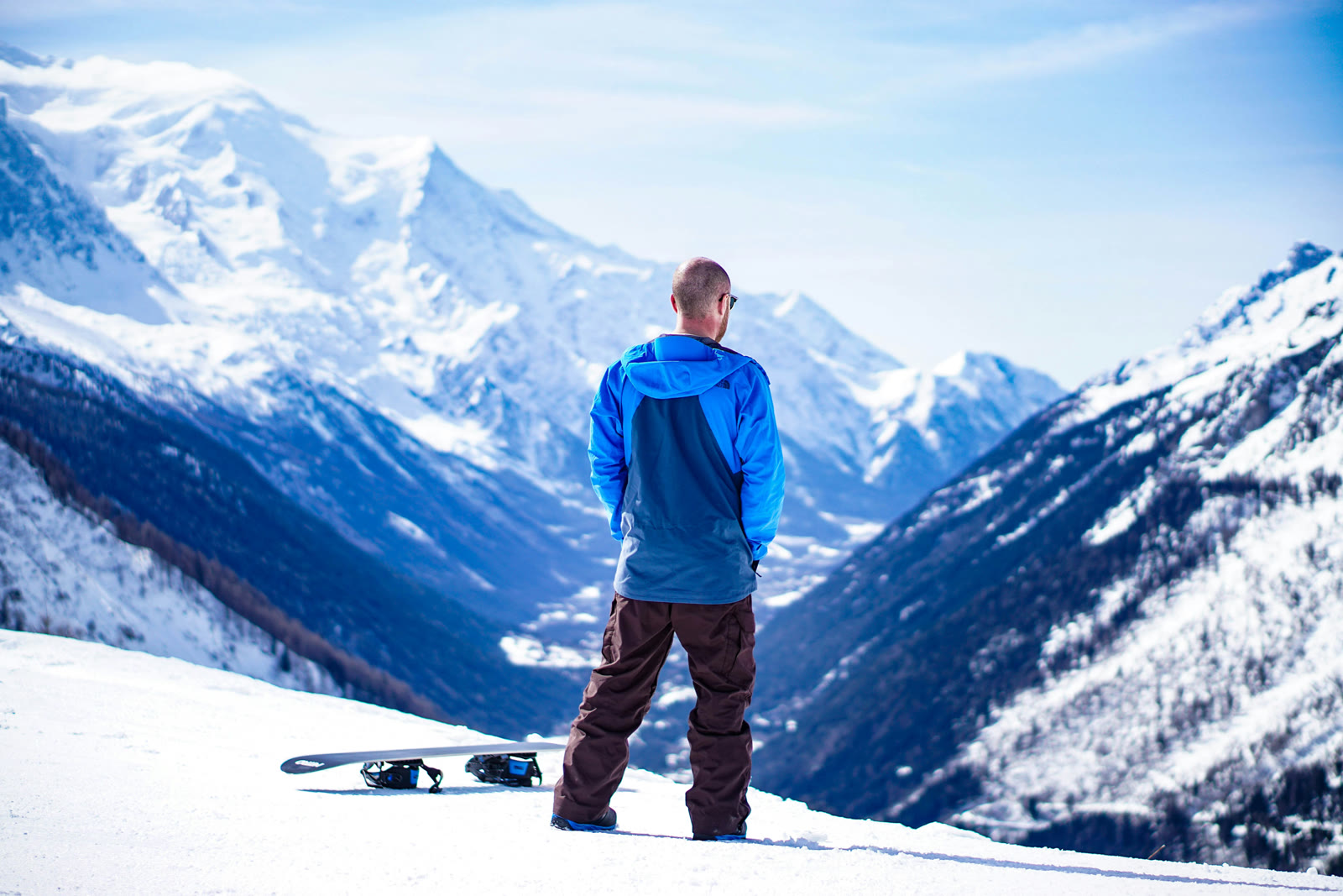 A rider looking out over a snowy mountain with skis in the snow