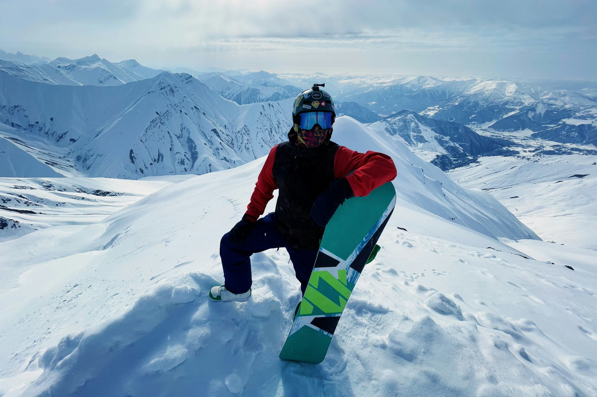 A snowboarder on a ridge with a mountain range behind them